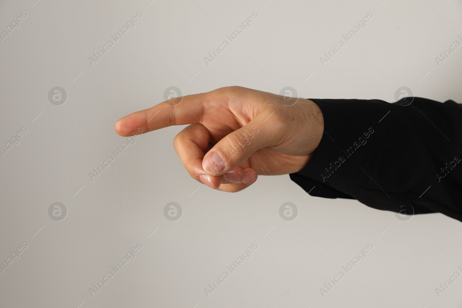 Photo of Man pointing at something on light background, closeup