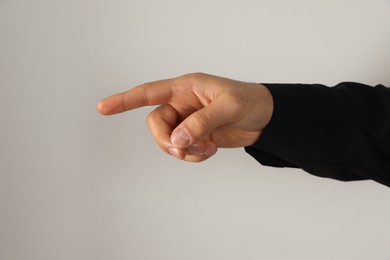 Man pointing at something on light background, closeup