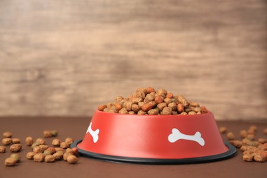 Dry dog food and feeding bowl on brown table. Space for text