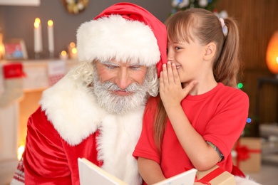 Little child with Santa Claus at home on Christmas day