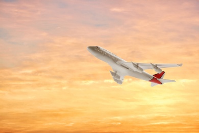 Airplane flying in sky at sunset. Air transportation