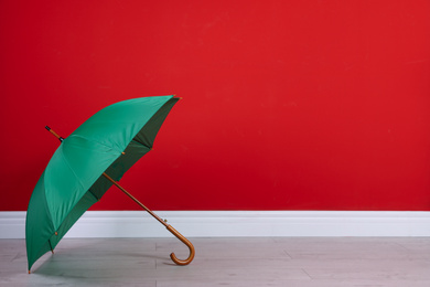 Photo of Beautiful green umbrella near red wall. Space for text