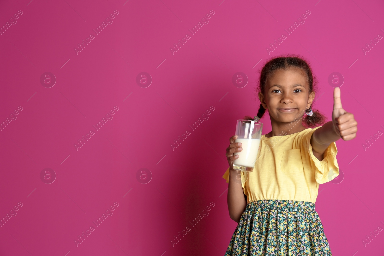 Photo of Adorable African-American girl with glass of milk on color background