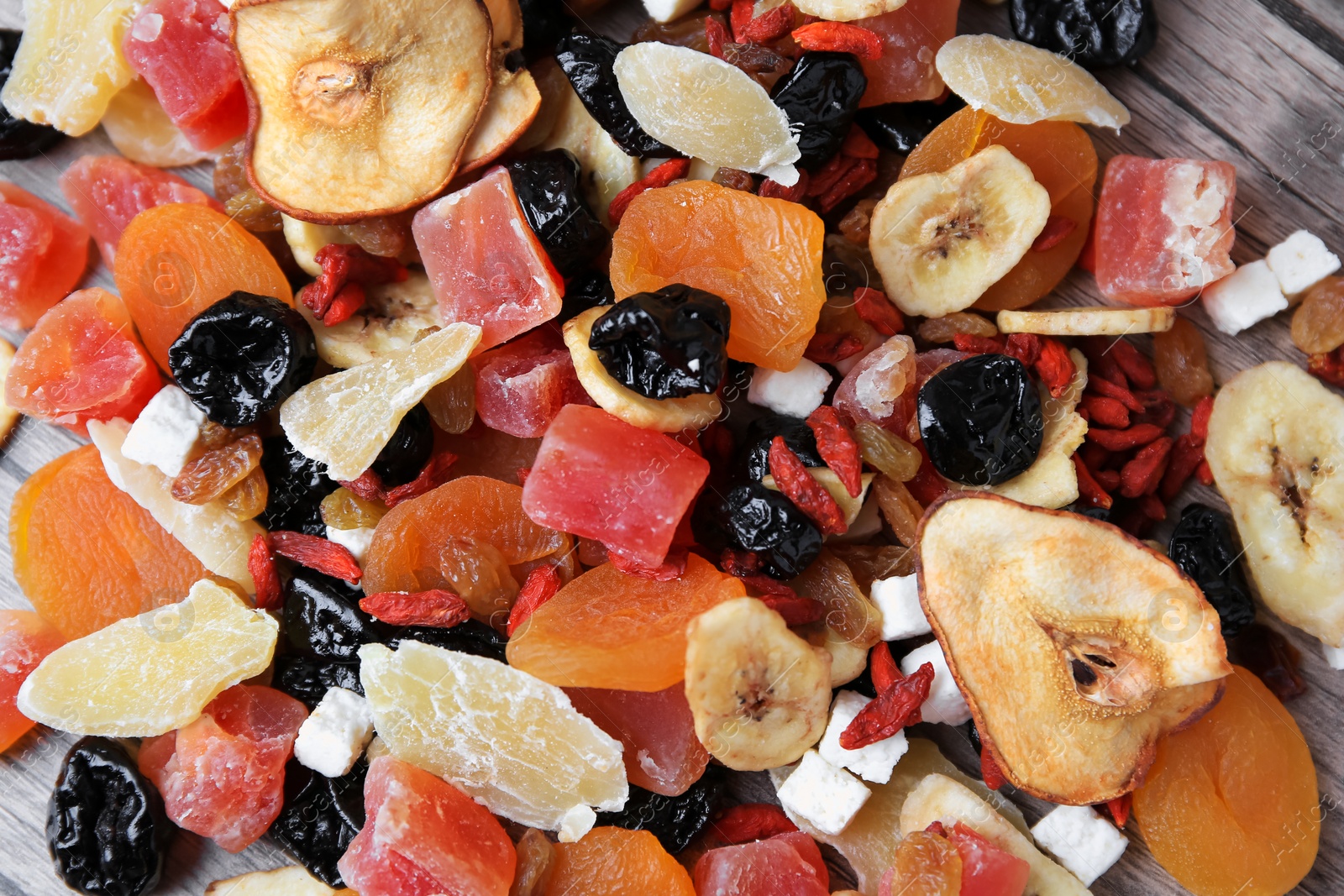 Photo of Pile of different tasty dried fruits on wooden table, flat lay