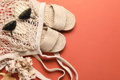 String bag, sunglasses, slippers, starfish and coral on color background, top view. Space for text