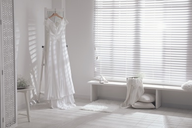 Beautiful wedding dress hanging on mirror in room