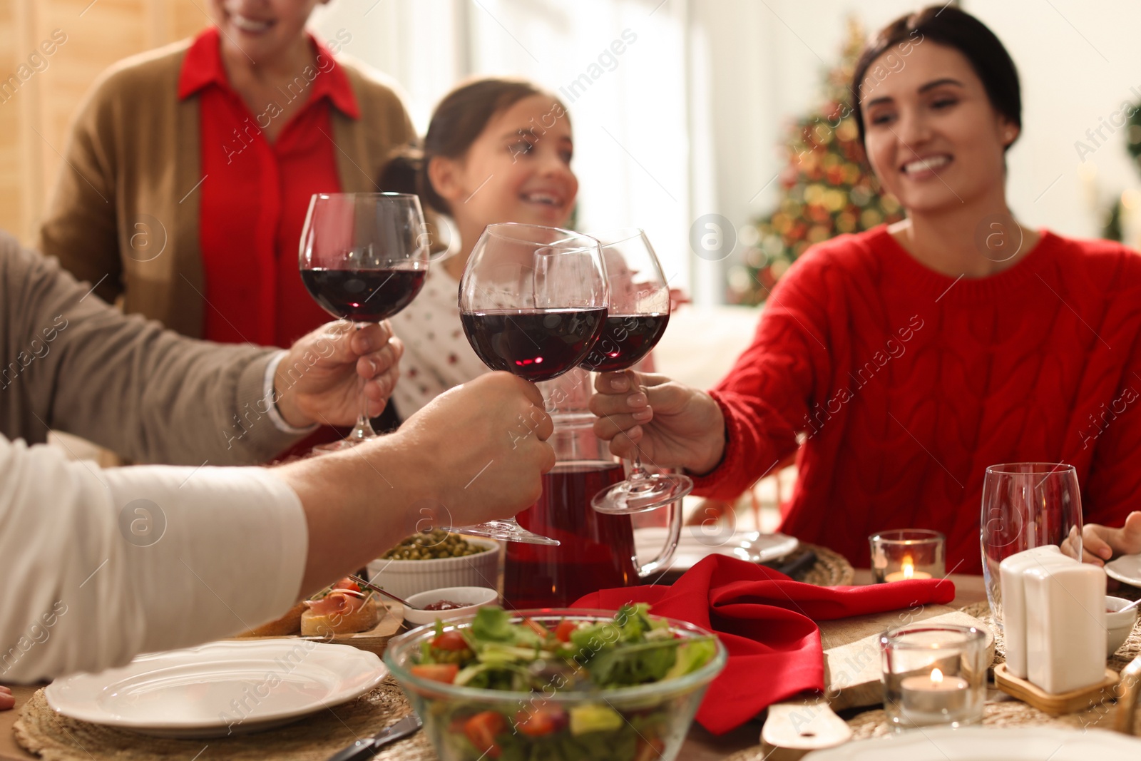 Photo of Family clinking glasses of wine at festive dinner, focus on hands. Christmas celebration