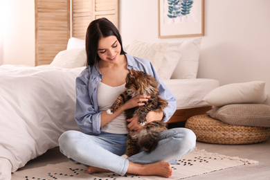 Photo of Beautiful young woman with her cute cat on floor in bedroom. Fluffy pet
