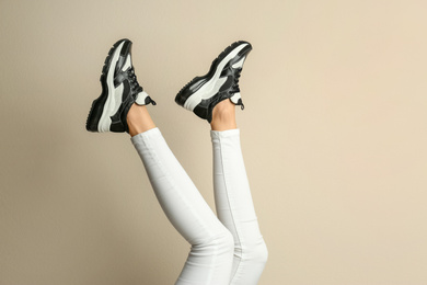 Woman wearing sneakers on beige background, closeup