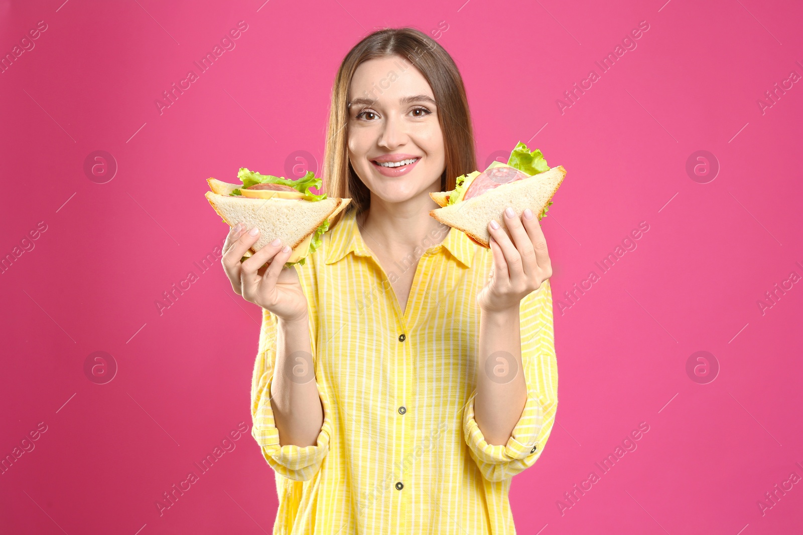 Photo of Young woman with tasty sandwiches on pink background