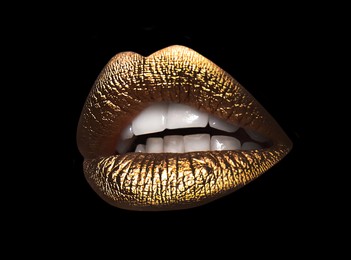 Image of Beautiful lips with shiny golden lipstick on black background