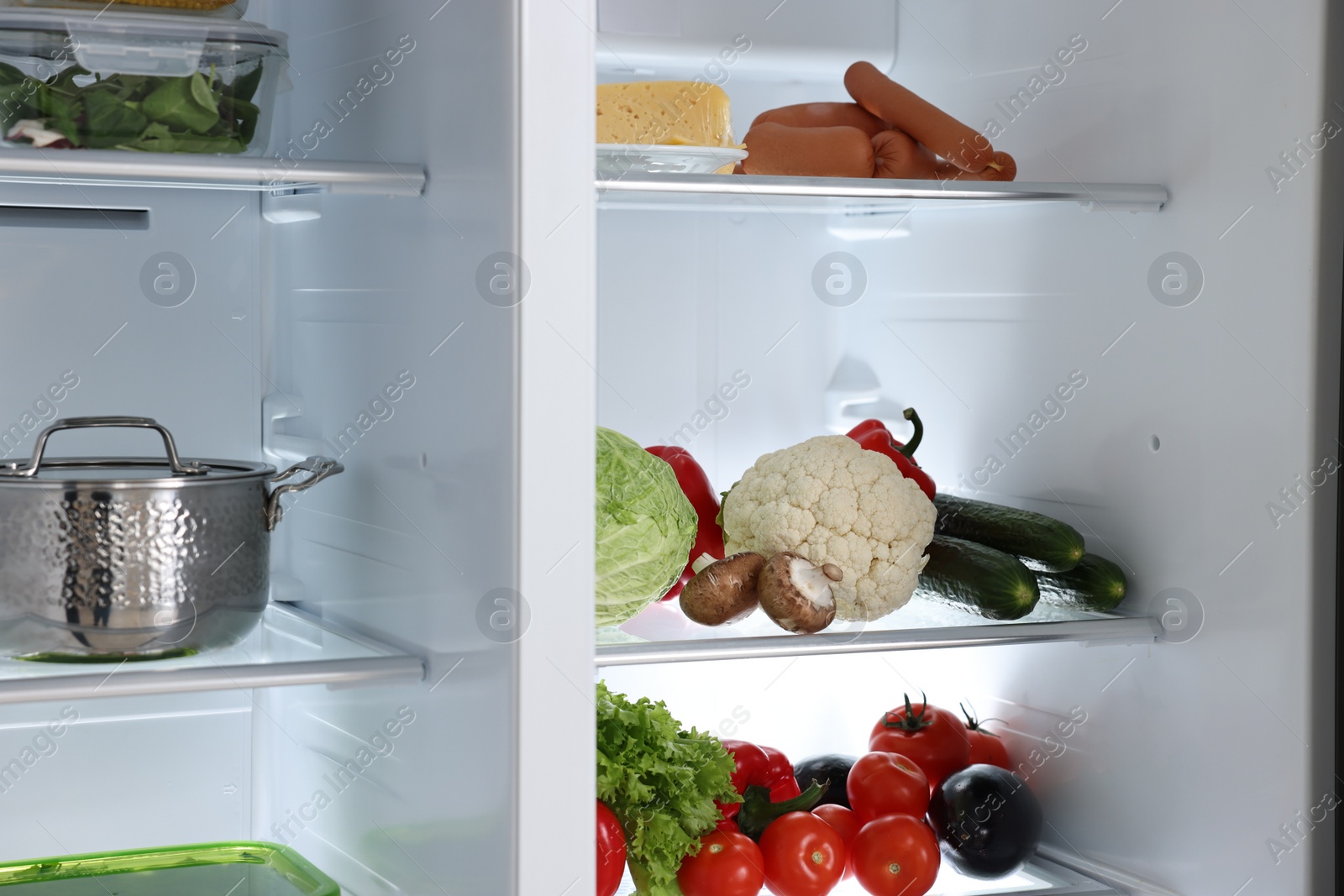 Photo of Open refrigerator full of different products indoors