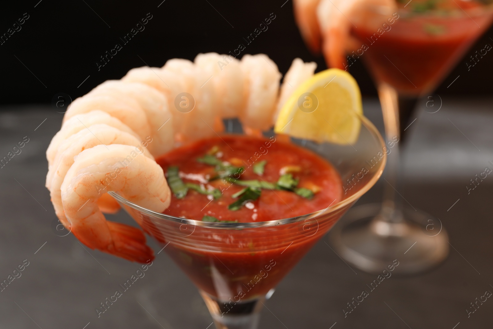 Photo of Tasty shrimp cocktail with sauce in glasses on grey table closeup