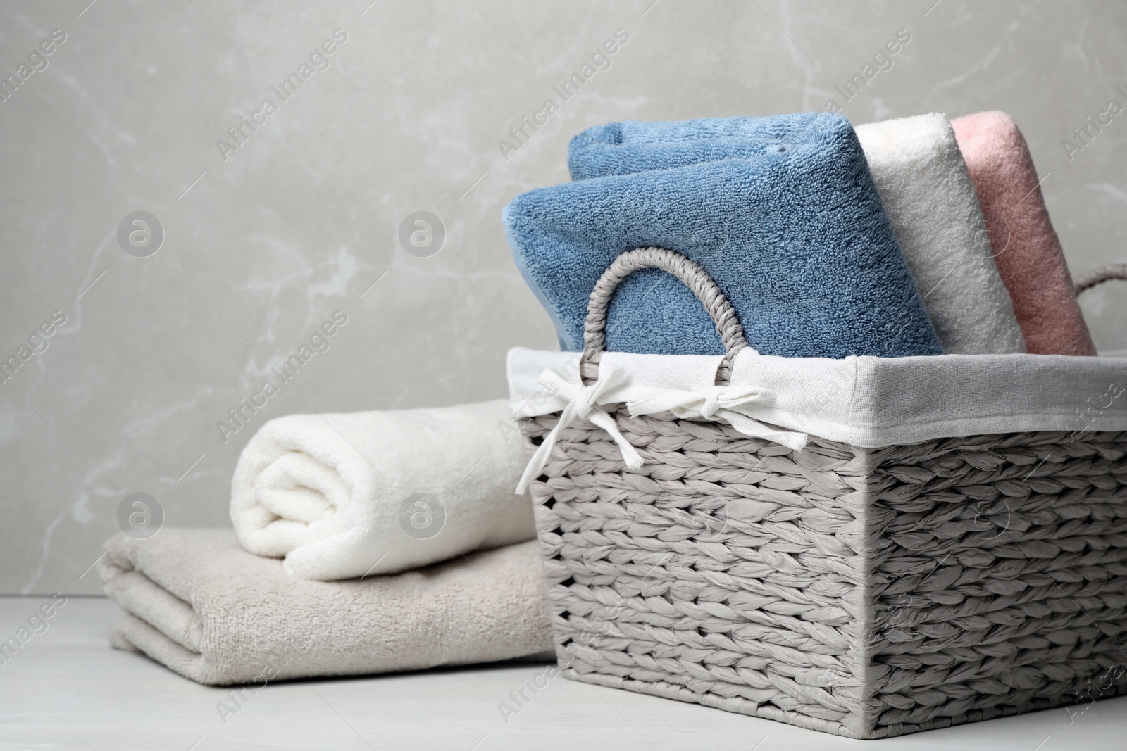 Photo of Wicker basket and fresh towels on table