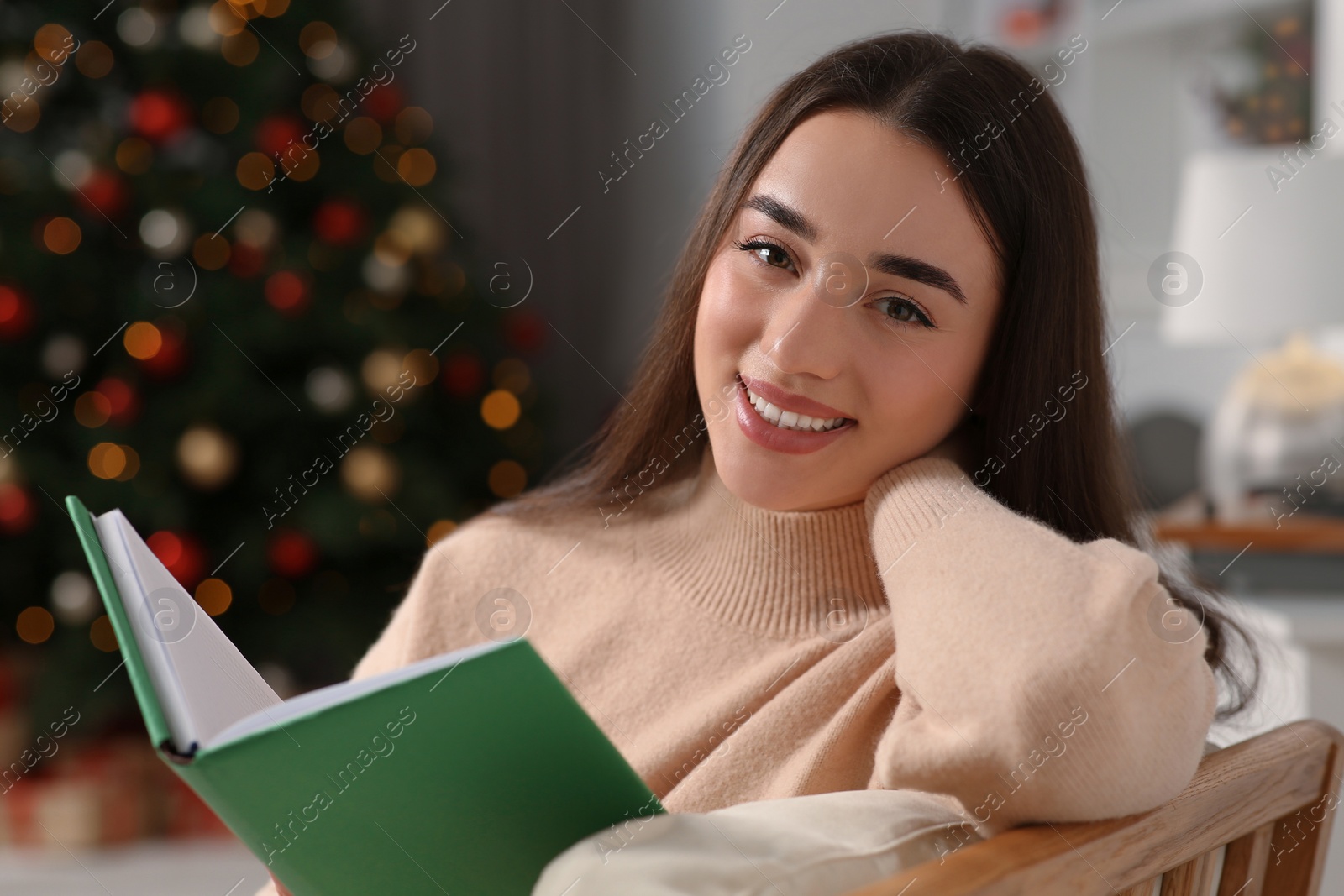 Photo of Christmas mood. Portrait of smiling woman with book indoors