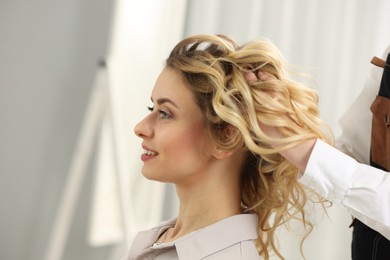 Hair styling. Professional hairdresser working with smiling client indoors, closeup