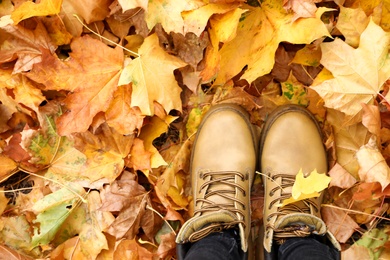 Woman standing on bright autumn leaves, top view