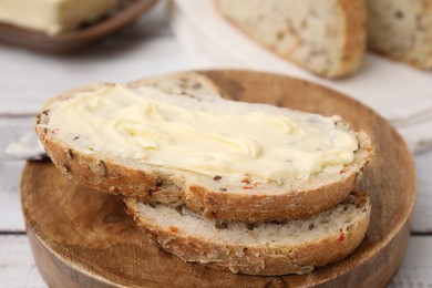 Slices of tasty bread with butter on white wooden table, closeup. Space for text