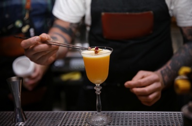 Bartender preparing tasty cocktail at counter in nightclub, closeup