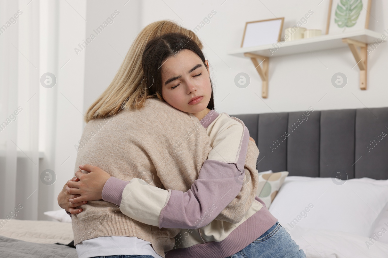 Photo of Mother consoling her upset daughter in bedroom. Teenager problems