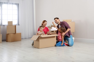 Photo of Family unpacking cardboard box in their new house. Moving day