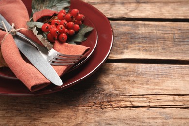 Festive table setting with ashberries on wooden background, closeup. Space for text