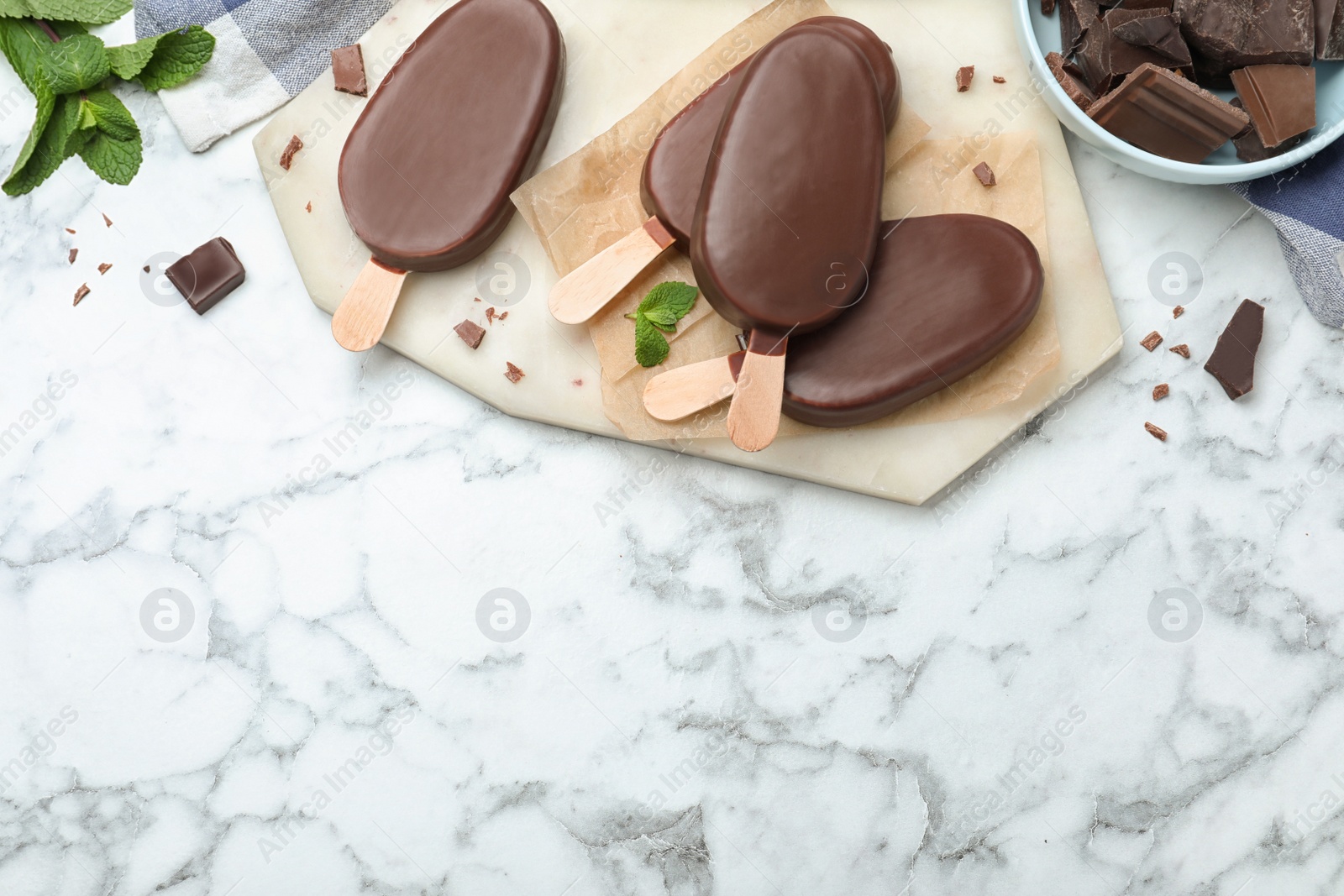 Photo of Delicious glazed ice cream bars with mint and chocolate on white marble table, flat lay. Space for text