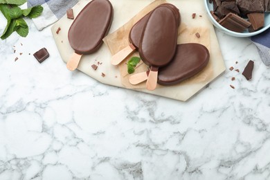 Photo of Delicious glazed ice cream bars with mint and chocolate on white marble table, flat lay. Space for text
