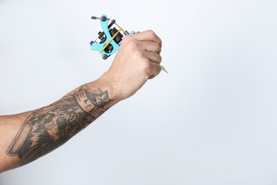 Photo of Professional tattoo artist with machine on white background, closeup