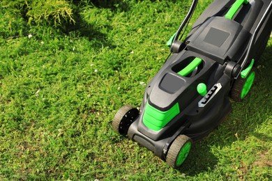 Photo of Lawn mower on green grass in garden, above view. Space for text