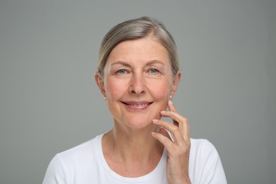 Portrait of senior woman with aging skin on grey background. Rejuvenation treatment
