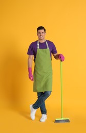 Man with green broom on orange background