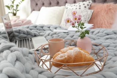 Photo of Tray with tasty breakfast and laptop on bed