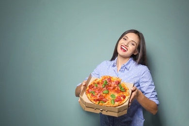 Photo of Attractive young woman with delicious pizza on color background