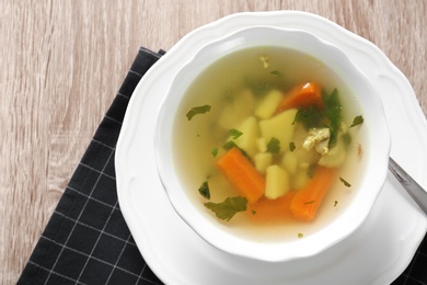 Photo of Bowl with delicious hot broth on table, top view. Cold treatment