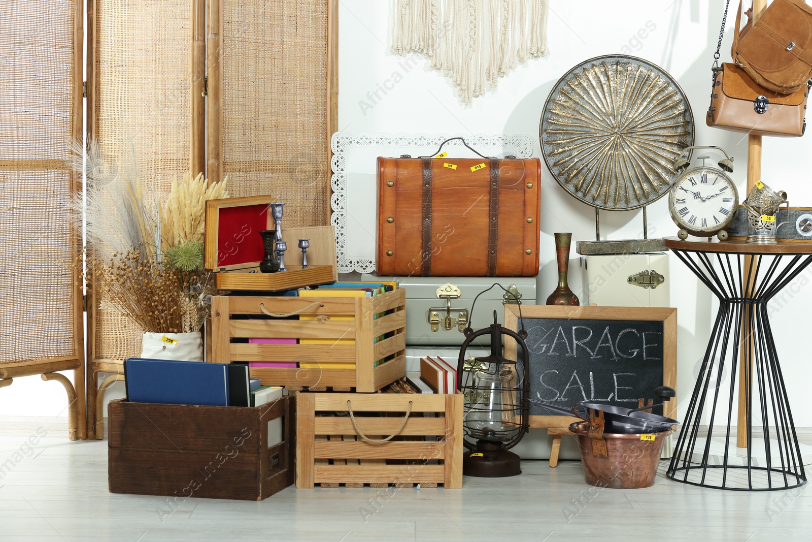 Photo of Sign Garage Sale written on blackboard near many different stuff indoors