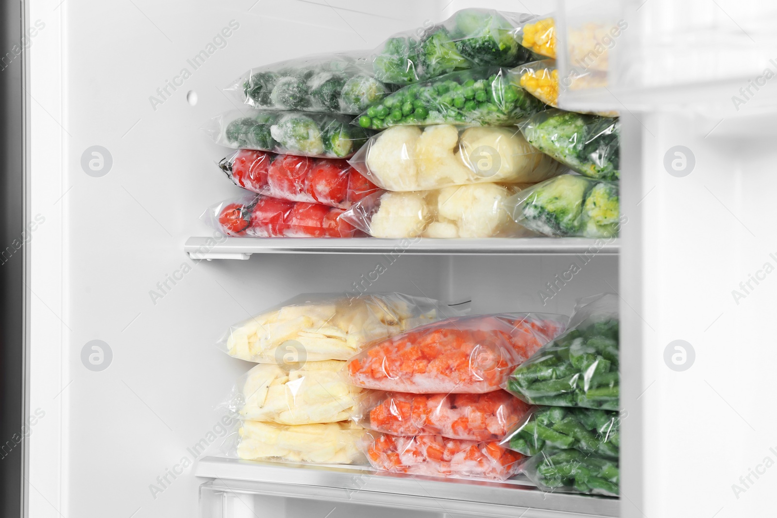 Photo of Plastic bags with different frozen vegetables in refrigerator