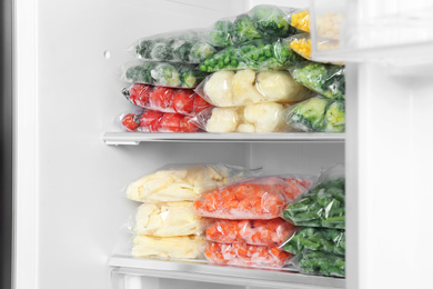 Photo of Plastic bags with different frozen vegetables in refrigerator