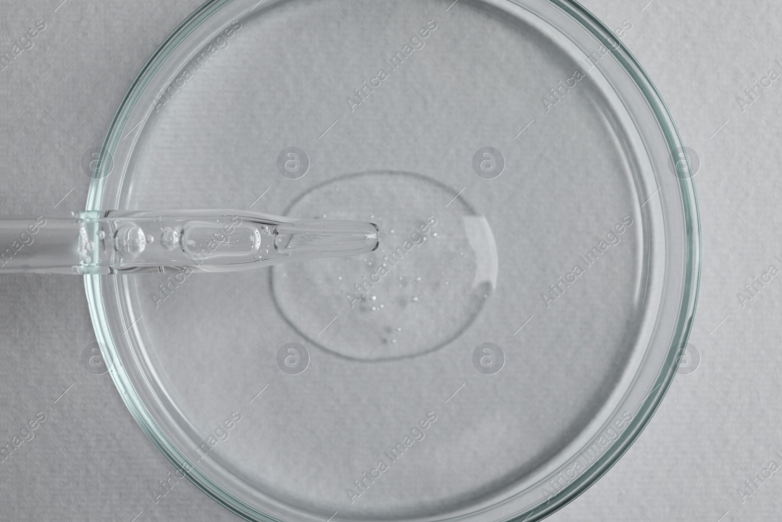 Photo of Petri dish with sample of cosmetic oil and pipette on white background, top view