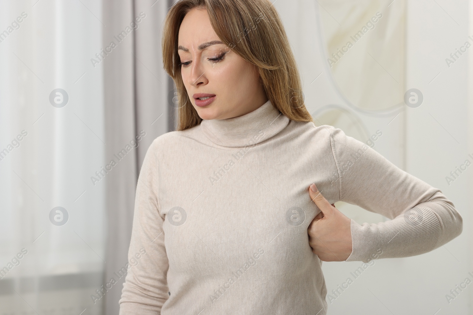 Photo of Mammology. Young woman doing breast self-examination at home