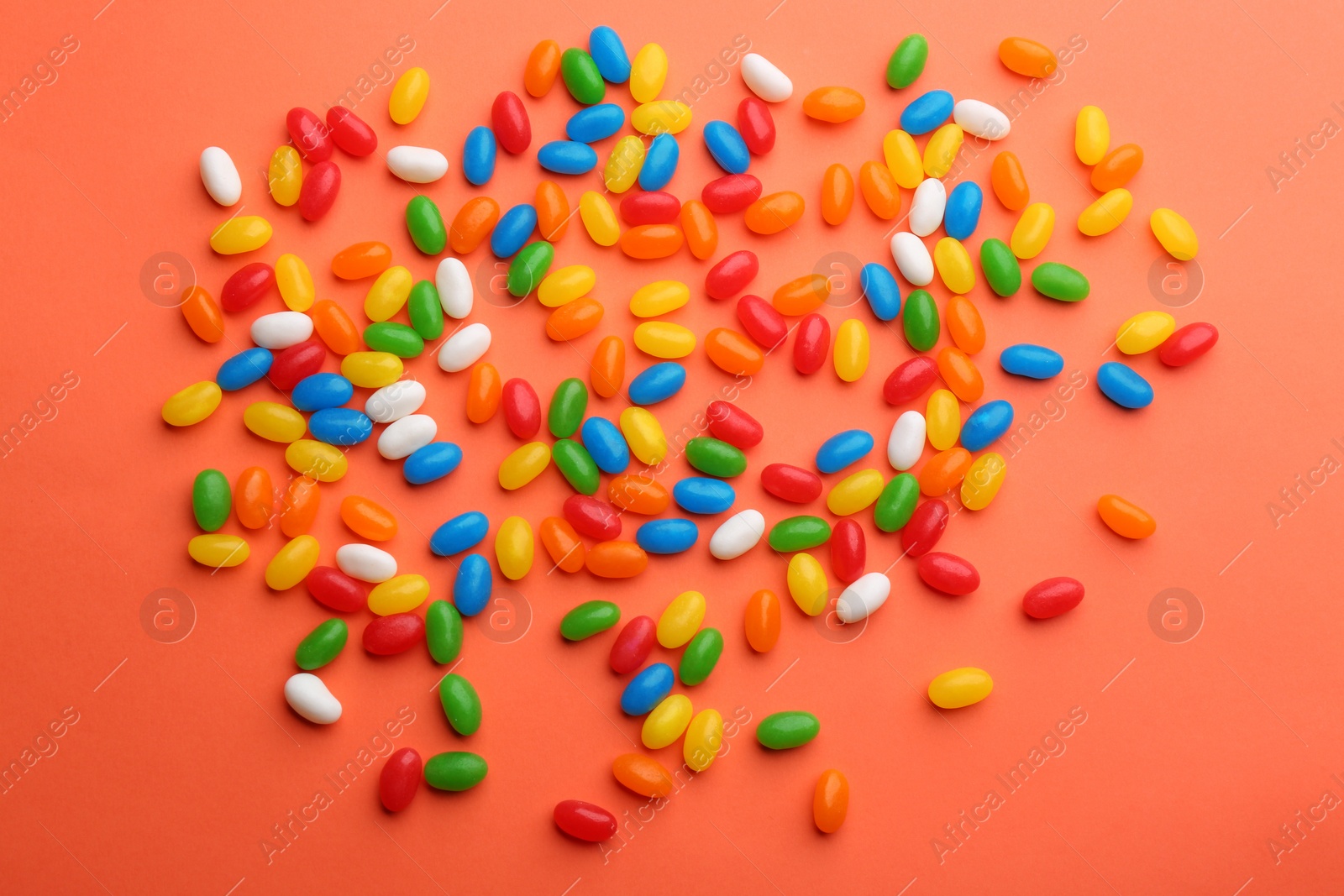 Photo of Colorful jelly beans on coral background, flat lay