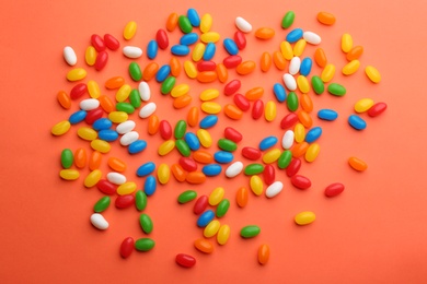 Colorful jelly beans on coral background, flat lay