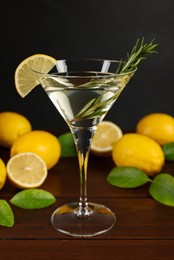 Martini cocktail with lemon slice, rosemary and fresh fruits on wooden table
