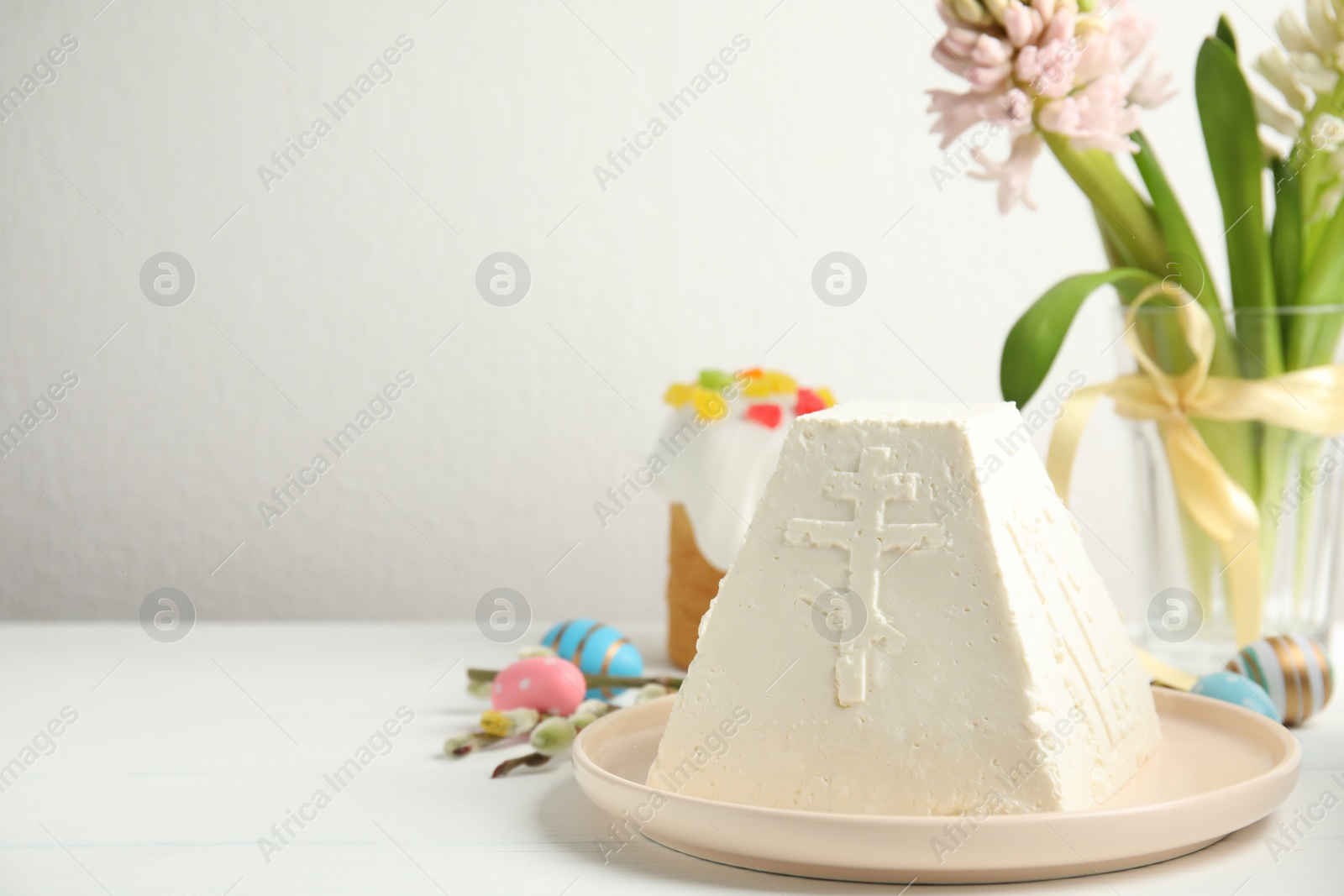 Photo of Traditional cottage cheese Easter paskha and eggs on white wooden table, space for text