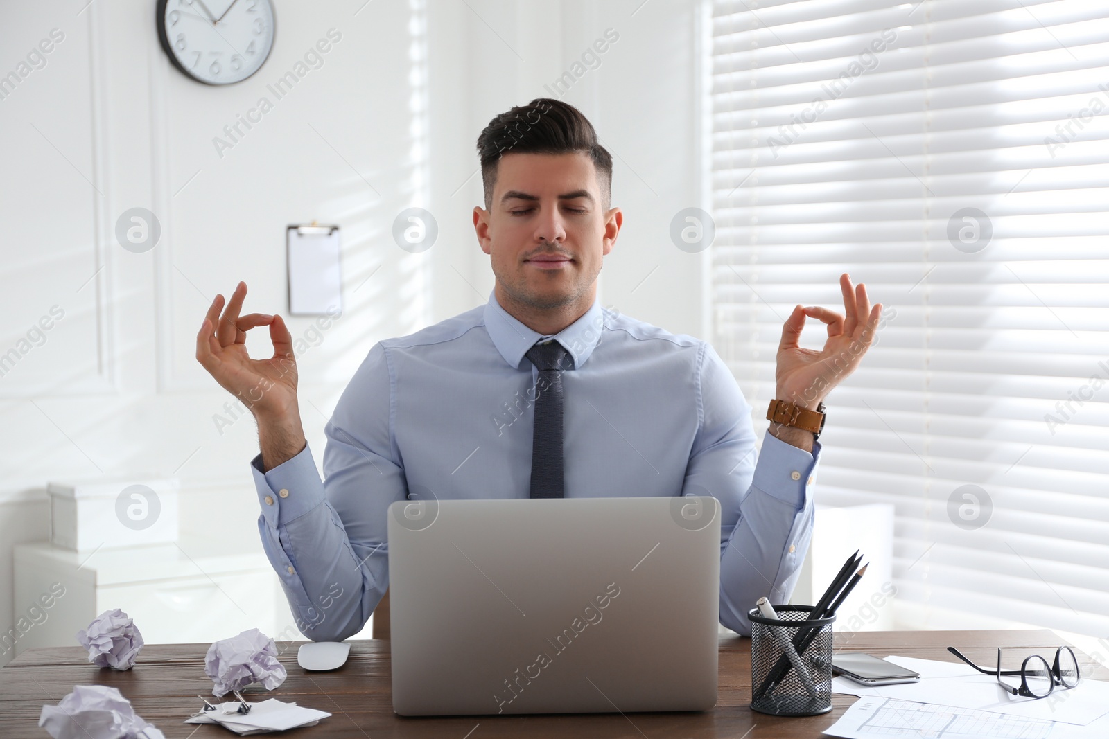 Photo of Businessman meditating at workplace in office. Stress relieving exercise