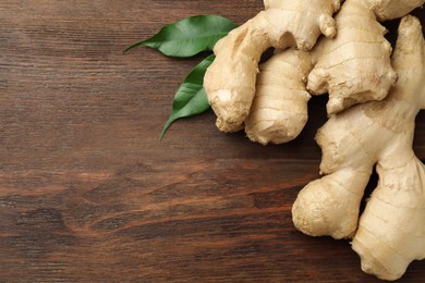 Fresh ginger with leaves on wooden table, top view. Space for text