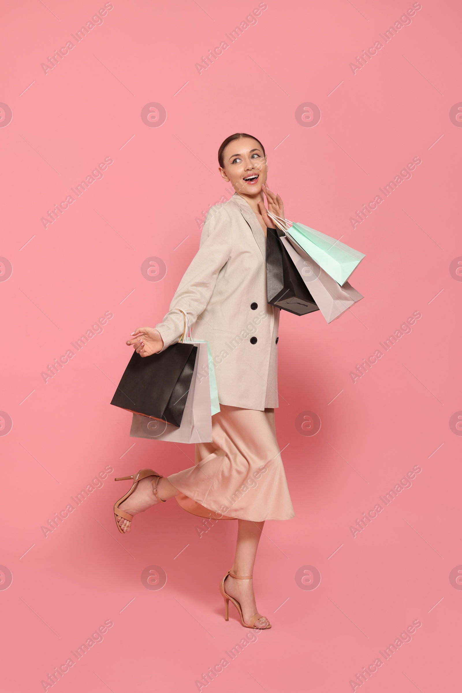 Photo of Stylish young woman with shopping bags on pink background