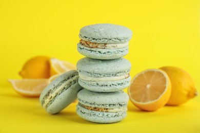 Photo of Delicious macarons and fresh lemons on yellow background