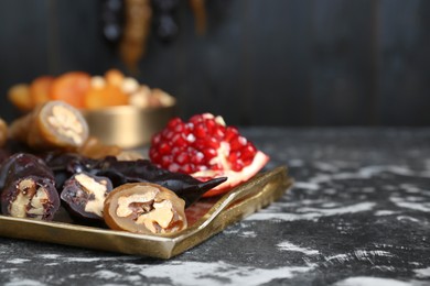 Photo of Delicious sweet churchkhelas and pomegranate on textured table, closeup. Space for text