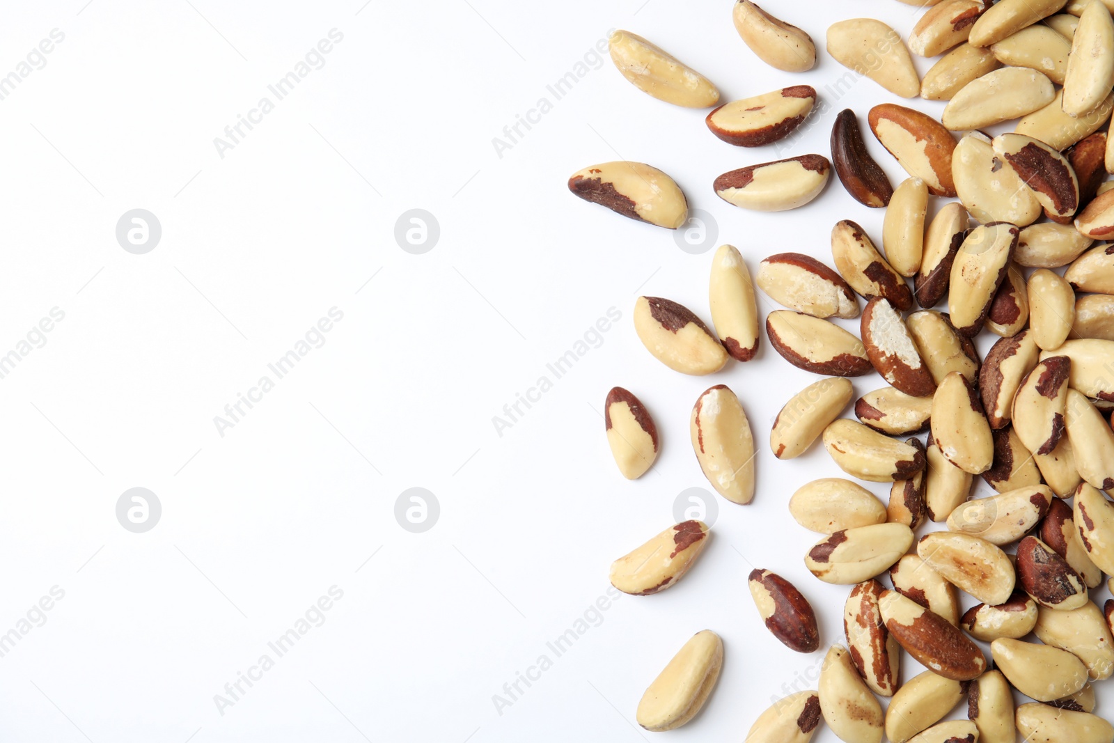 Photo of Many brasil nuts and space for text on white background, top view